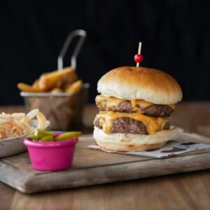 Mouthwatering cheeseburger served with fries and coleslaw on a wooden board.