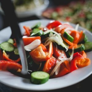 A vibrant fresh vegetable salad with cucumbers and peppers in a white bowl.