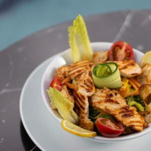 Delicious grilled chicken Caesar salad with fresh vegetables served on a marble table.